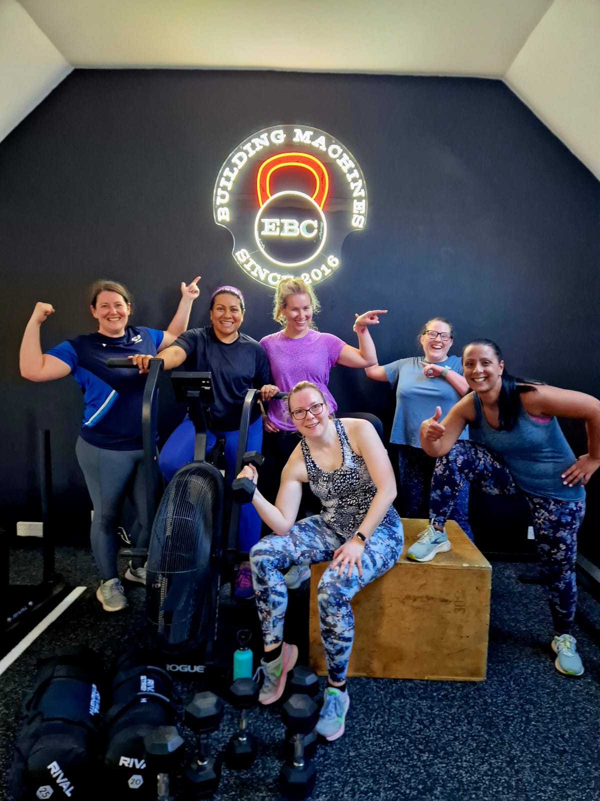 Members posing with the kit in front of the EBC Gym's neon sign